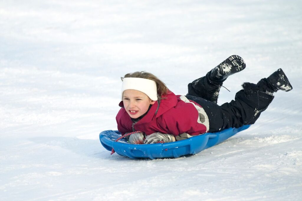 Enfants descendant en luge sur une pente enneigée d’un espace luge de station de montagne