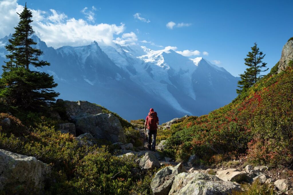 Randonneur équipé d’un sac à dos devant un panorama de montagne au printemps